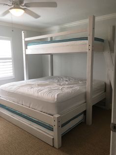 a white bunk bed sitting in a bedroom next to a window with blinds on the windowsill