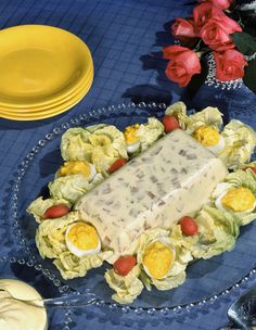 a plate topped with lettuce covered in sauce next to yellow plates and flowers