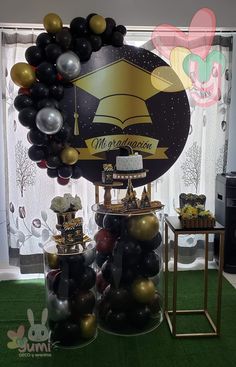 balloons and decorations are displayed in front of a graduation balloon arch with an image of the graduate's cap on it