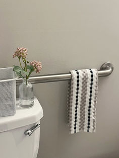 a white toilet sitting next to a bathroom sink with a towel hanging on it's side