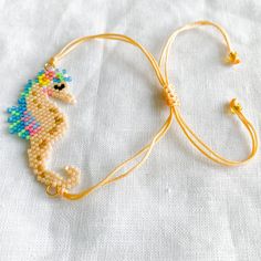 a close up of a beaded necklace on a white cloth with a yellow cord