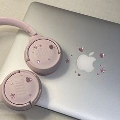 two pink headphones sitting on top of an apple laptop