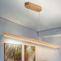 two paintings are hanging on the wall above a dining room table and bench in front of an overhead light fixture