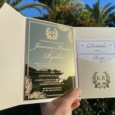 a person holding up a wedding card in front of some palm trees and blue sky