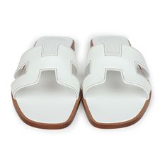 This pair of Oran Sandals are in white box leather with contrast stitching and feature the iconic H crossover strap. Origin: ItalyCondition: New and never wornAccompanied by: Hermes box, 2 shoe dustbagsSize: 38 EU White Hermes Sandals, Hermes Oran Sandals White, Hermes Oran Sandals, Hermes Oran, Hermes Box, Rug Bag, Hermes Birkin 30, School Bags For Kids, Backpack Tote Bag