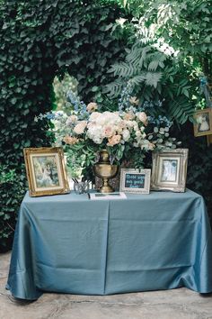 a table topped with pictures and flowers on top of a blue cloth covered tablecloth