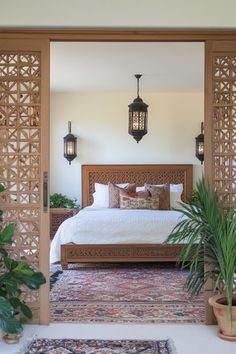 a large bed sitting in the middle of a bedroom next to a potted plant