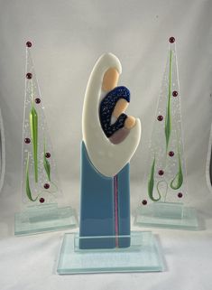 a glass figurine holding a baby in it's arms on top of a blue base