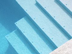 an empty swimming pool with steps leading up to the water's edge and blue tiled walls