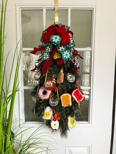 a christmas wreath hanging on the front door with ornaments around it and a potted plant next to it