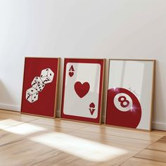 three framed pictures with playing cards on the floor in front of a white wall and wooden floors