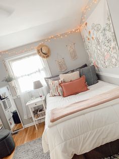 a white bed sitting in a bedroom next to a window with string lights on it