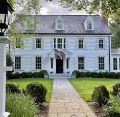 a white house with an american flag on the front door and walkway leading to it