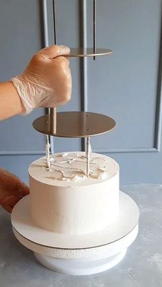 a person holding a knife over a white cake