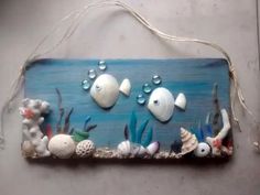 a wooden sign with sea shells and other marine life on the bottom, hanging from a rope