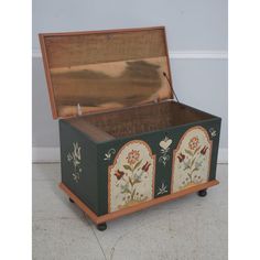 an old wooden chest with floral designs painted on the front and sides, sitting against a wall