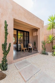 a house with a cactus in front of it and two chairs on the back patio