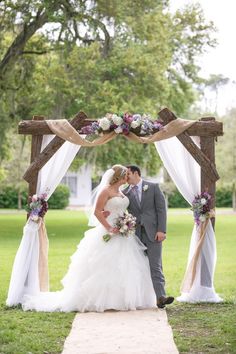 a bride and groom standing under an arch with flowers on it at their wedding ceremony