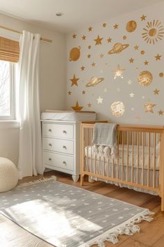 a baby's room with gold stars and planets on the wall, along with a white crib