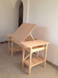 two wooden tables sitting next to each other on top of a cement floor in front of a doorway