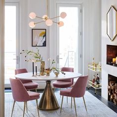 an elegant dining room with pink chairs and a white table surrounded by gold candlesticks