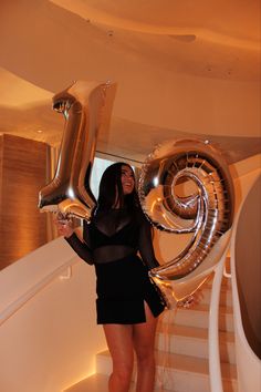 a woman holding some balloons in her hand and standing on the stairs at an event