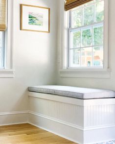 a white bench sitting in the corner of a room next to two windows with blinds on them