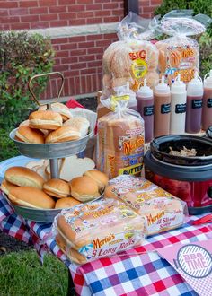 an assortment of hot dogs and buns on a picnic table with other food items