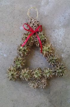 a christmas ornament made out of pine cones with a red ribbon hanging from it