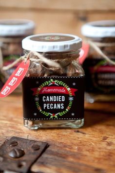 three jars filled with candied pecans sitting on top of a wooden table