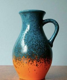 a blue and orange vase sitting on top of a wooden table