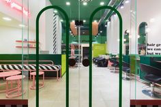 the interior of a hair salon with green and pink chairs, mirrors, and neon lights