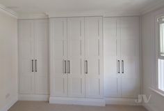 an empty room with white cupboards and windows