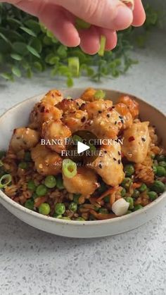 a bowl filled with chicken and peas on top of rice