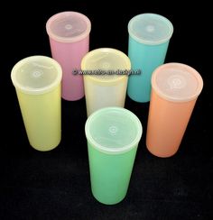 six different colored plastic cups sitting next to each other on a black surface with one empty cup in the middle