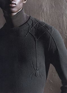 a woman in a black turtle neck top with a spider web design on her chest