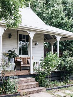 a small white house with steps leading up to the front door and covered porch area