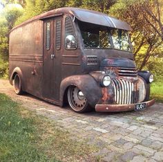 an old truck is parked on the side of the road in front of some trees