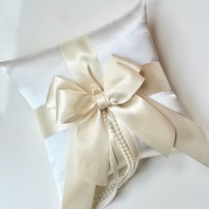 a white pillow with a satin bow and pearls on the side, tied to it