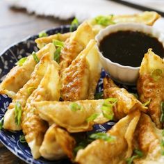 a blue plate topped with wontons and dipping sauce