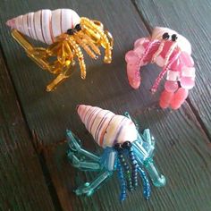 three sea animals made out of glass beads on a wooden surface, one is pink and the other is blue