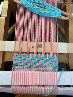 the loom is being worked on by someone using two different colors of yarns