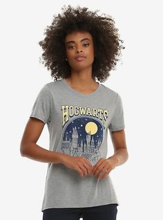 a woman standing in front of a white background wearing a hogwarts t - shirt