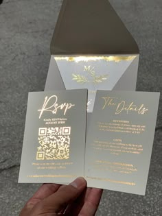 someone is holding up two wedding cards with gold foil on the front and back side