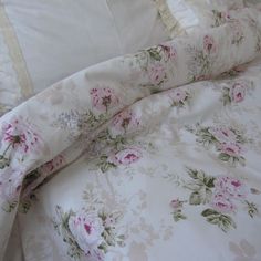 an unmade bed with white sheets and pink flowers on it's comforter