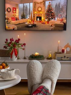 a person's feet in slippers sitting on a chair with christmas decorations and candles