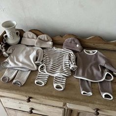 several knitted items are sitting on top of a wooden dresser next to a coffee mug