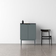 a chair and cabinet in an empty room with a white wall behind it, next to a black chair