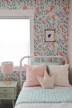 a bedroom with floral wallpaper and pink accents