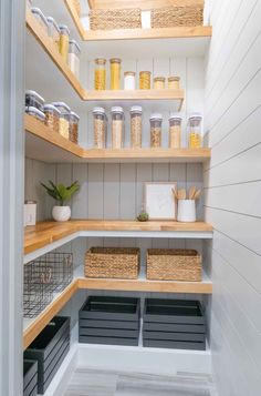 an organized pantry with wooden shelves and baskets